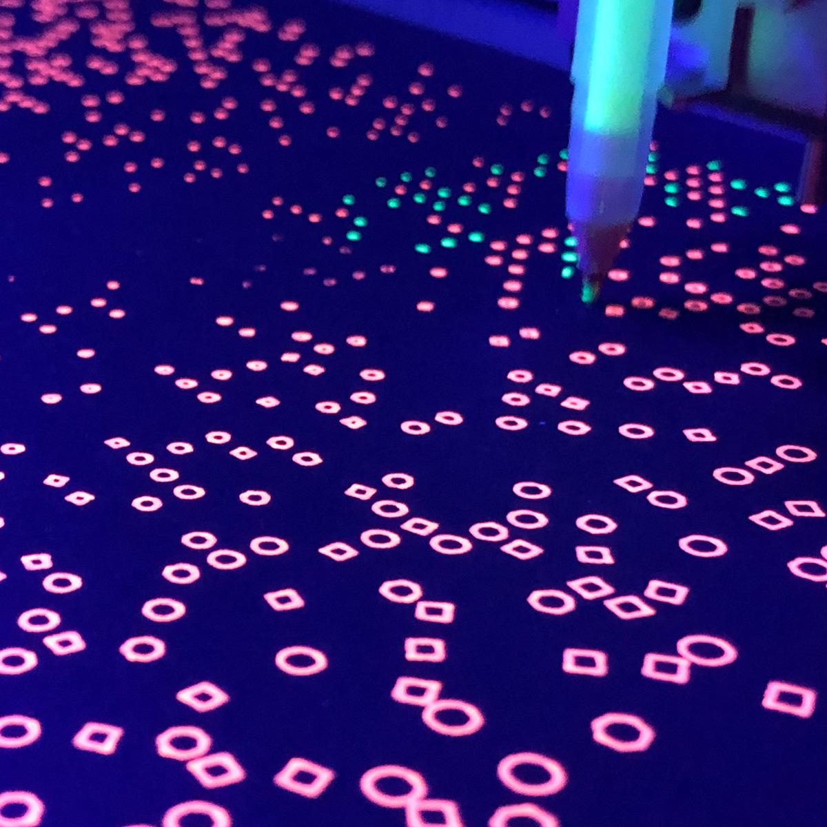 A printing-in-progress shot of green shapes being added in spaces between a completed orange layer